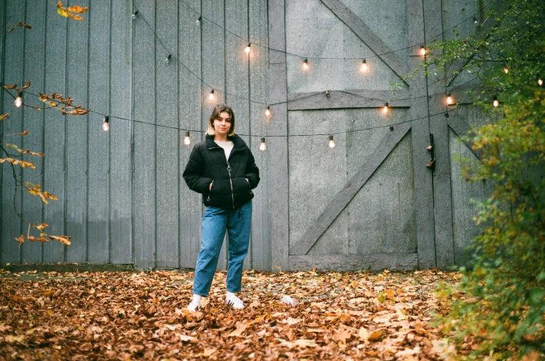 a person standing in leaves next to a fence