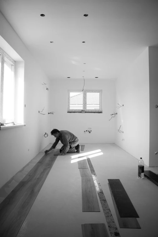 a man kneeling in a room painted white