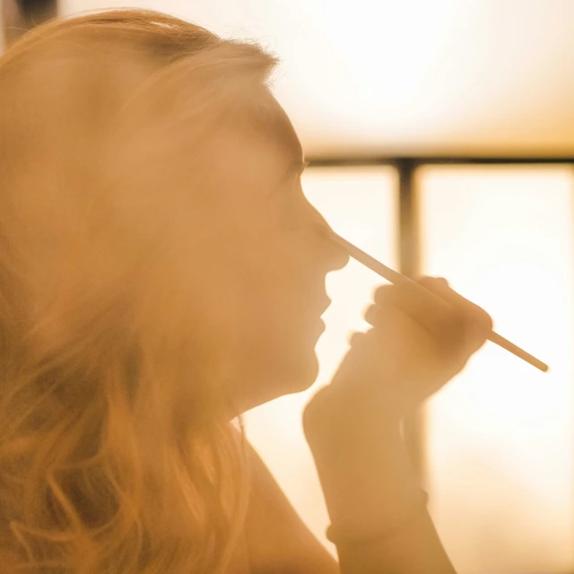 a woman holds soing in her mouth while smoking