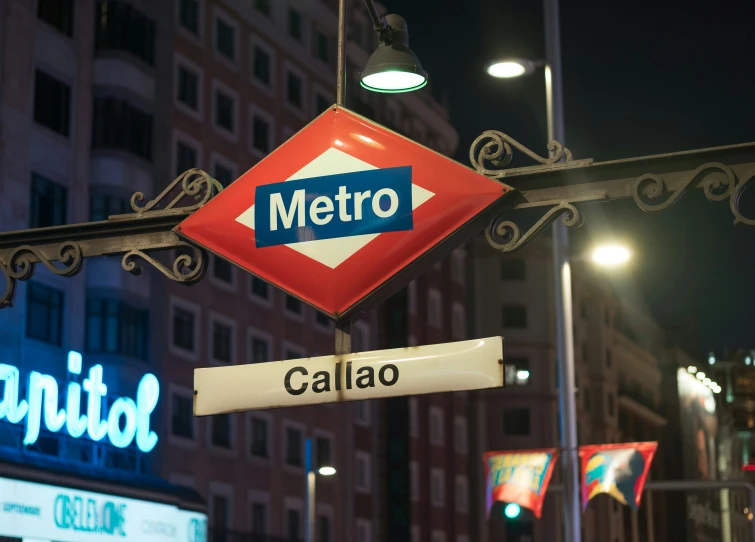 a metro sign with neon signs hanging from it