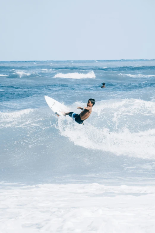 a man riding on top of a white surfboard on top of water