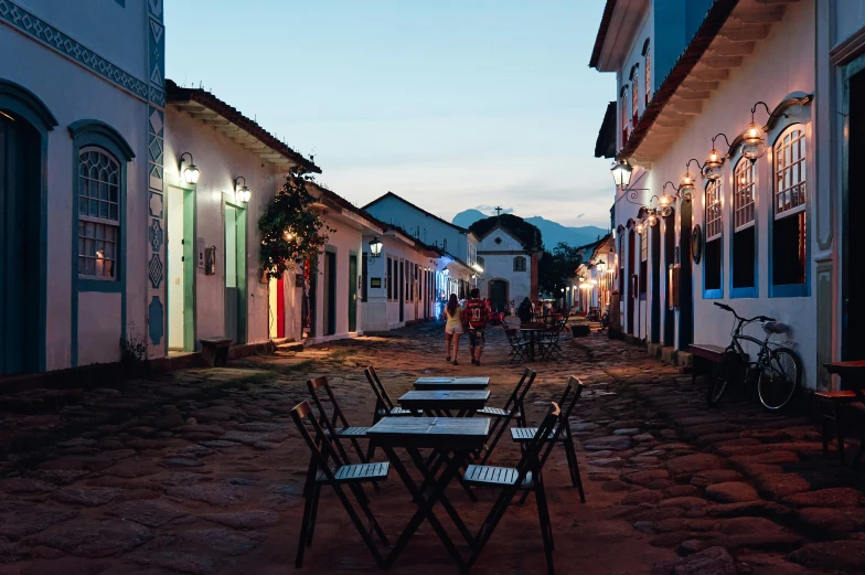 a cobblestone street filled with small tables and chairs