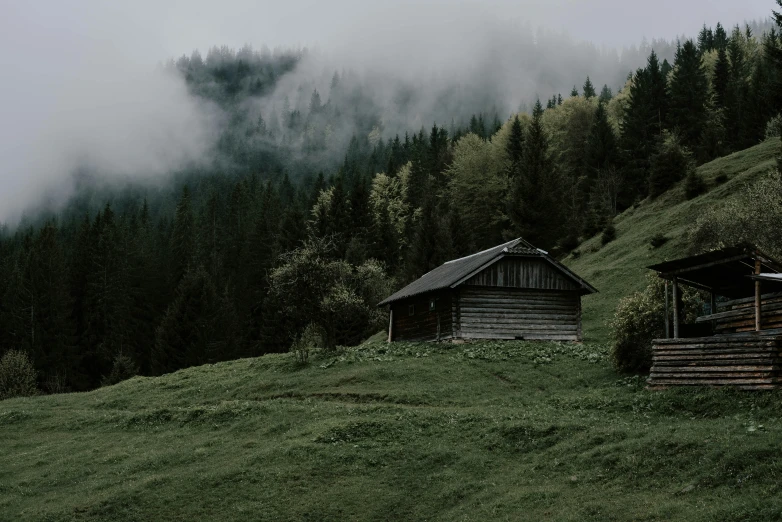 two small wooden cabins on top of a green hillside