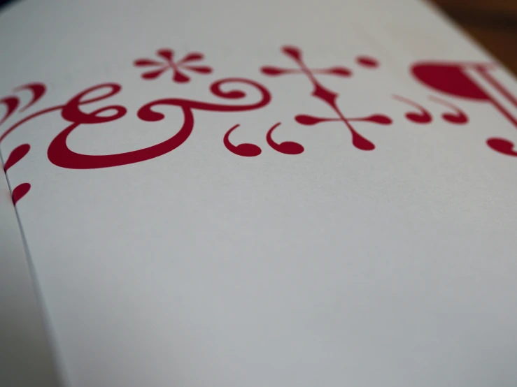 the corner of a white paper with red designs on it