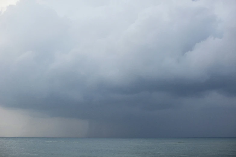 a lone surfer walking into the ocean under a gray sky