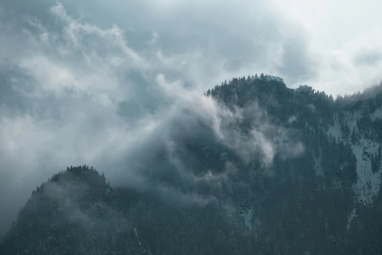 clouds rolling over the tops of mountains during a rain storm