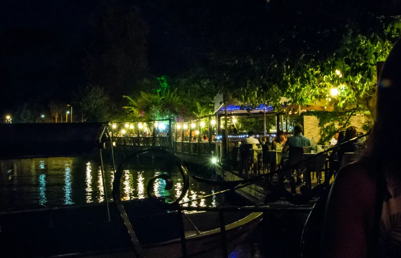 people on the water at night with boats docked nearby