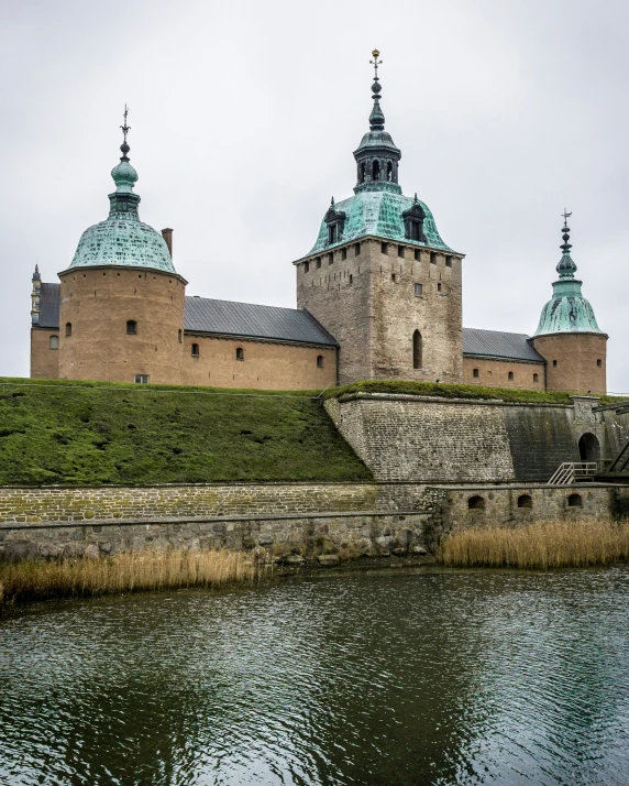 a castle sitting next to a river near tall buildings