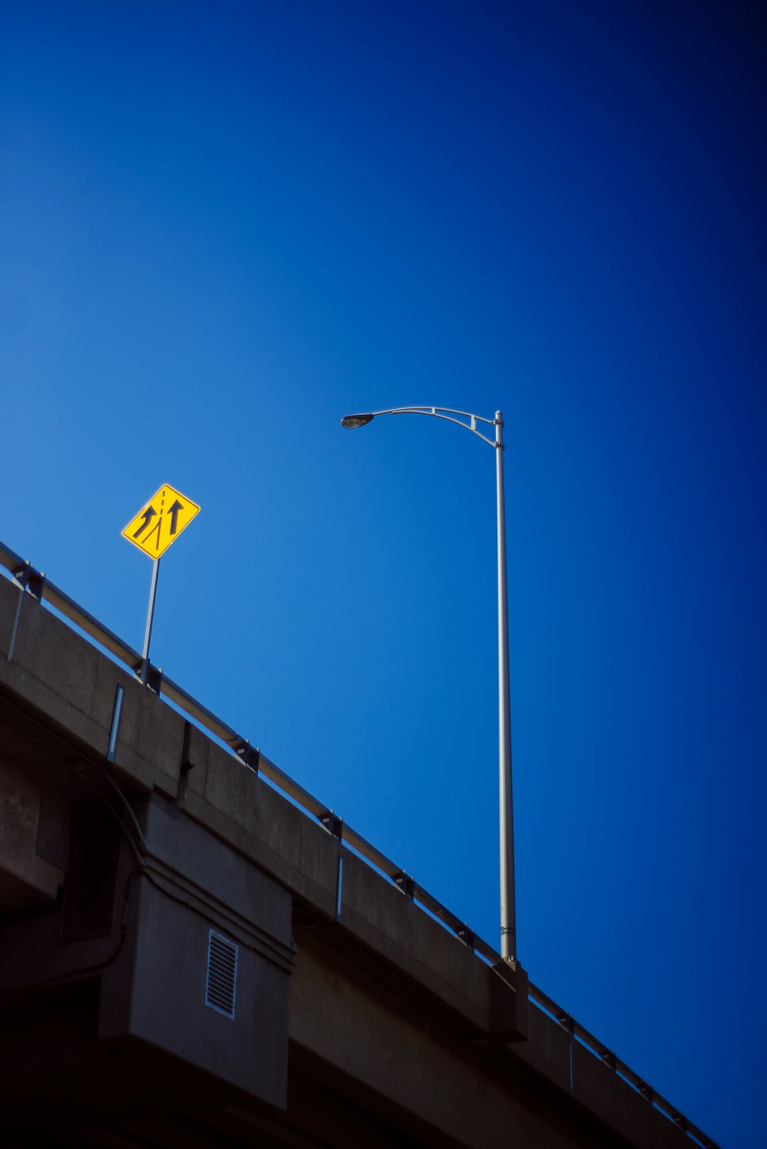 an orange street sign hanging above the top of a bridge