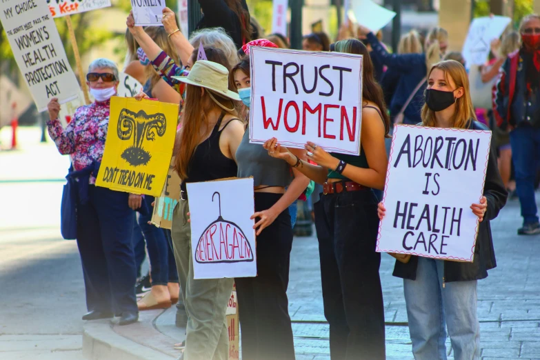 a group of people holding signs that say trust women
