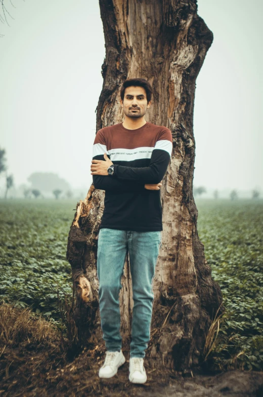 a young man standing in front of a tree