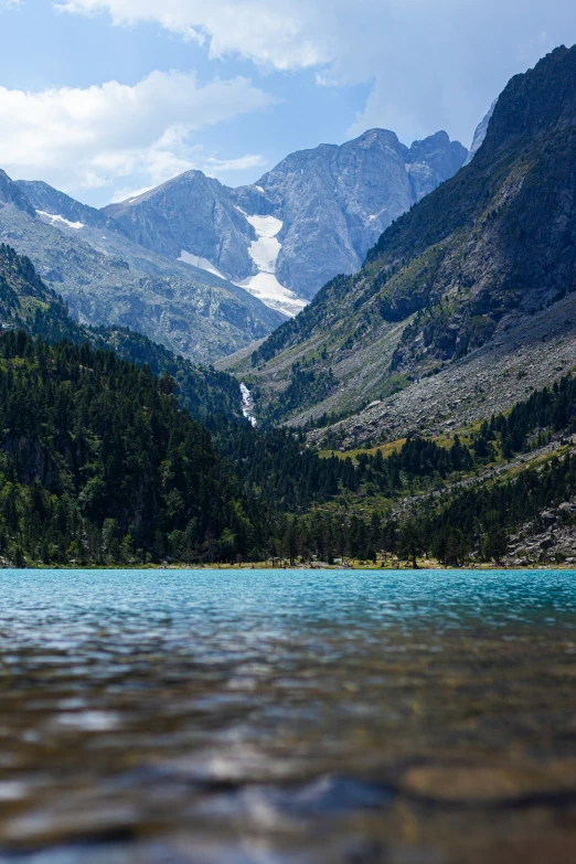 water on the edge of a river below snow capped mountains