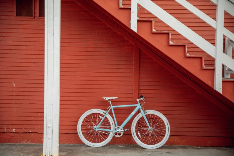 a blue bike parked underneath a red stairwell