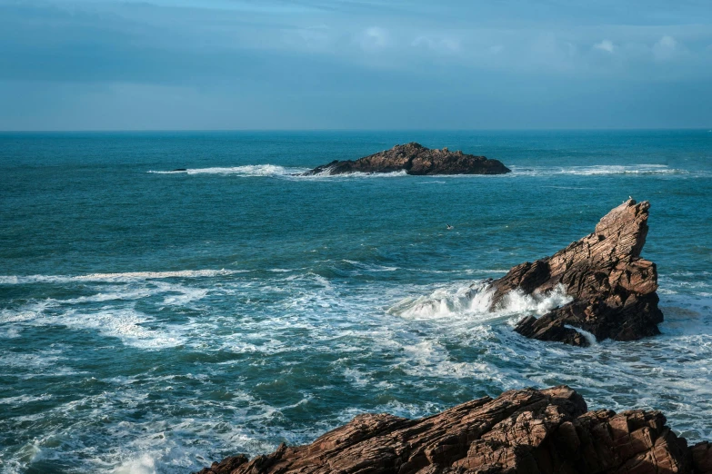 a body of water next to rocks near shore