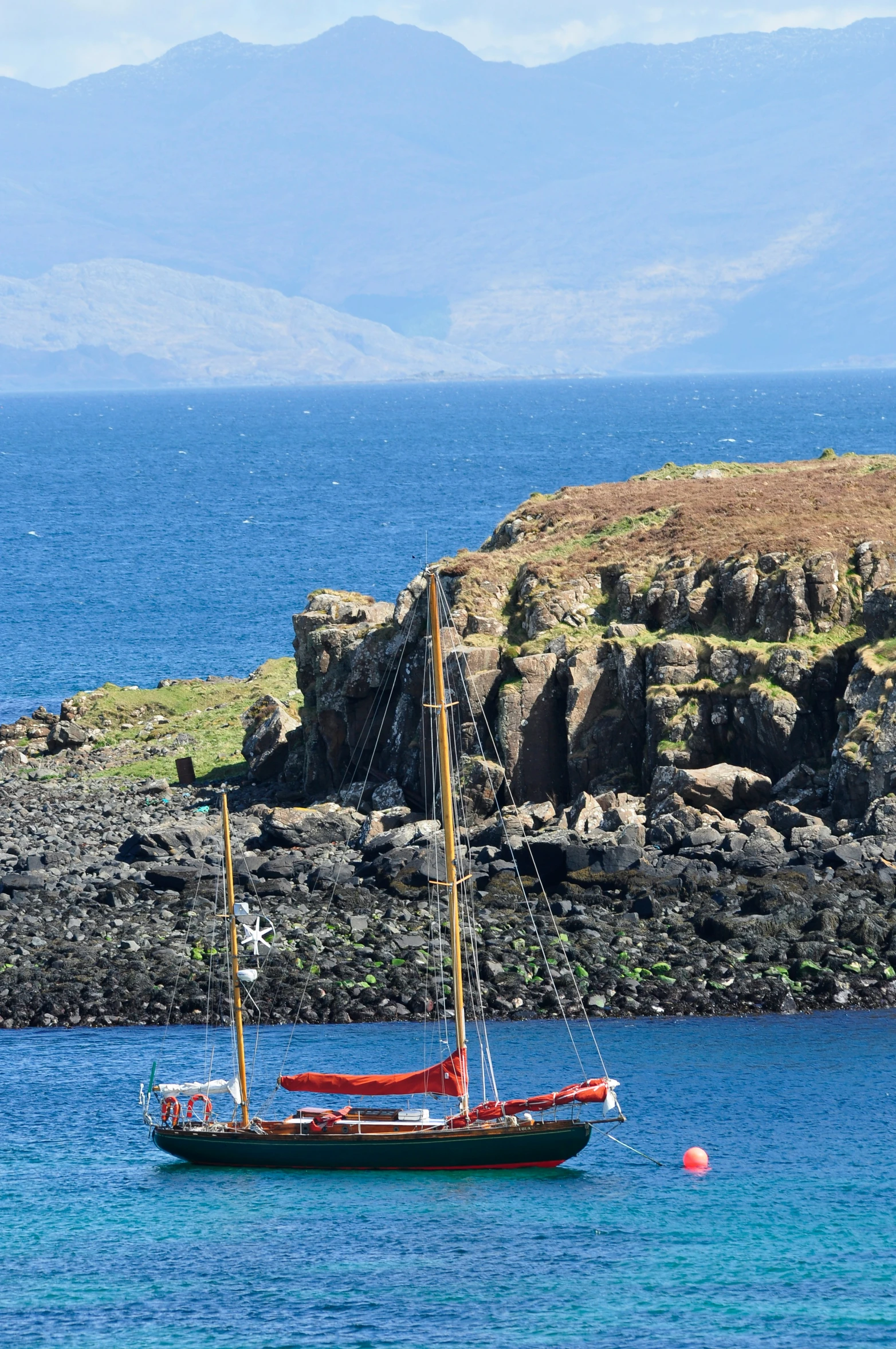 a small sail boat sitting at anchor in a calm harbor