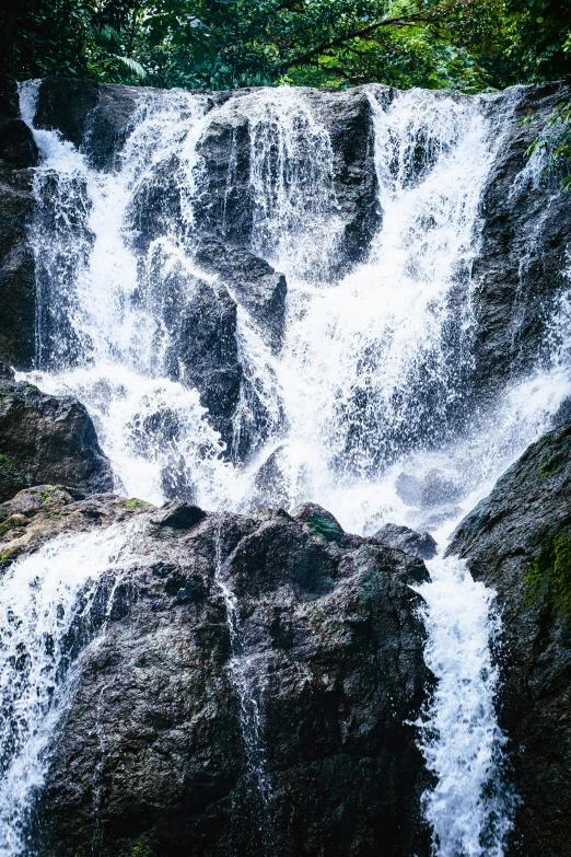 several brown rocks are near a large waterfall