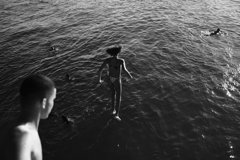 a person is walking in the water towards a woman who is looking at them
