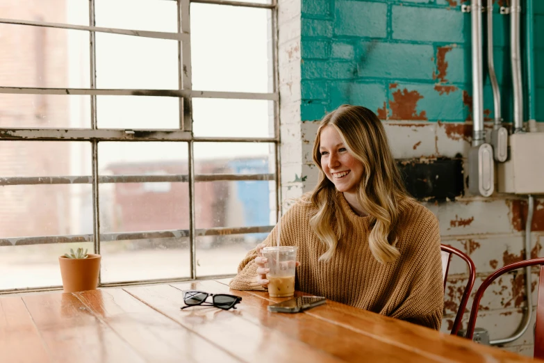 a woman sitting at a table with a coffee mug