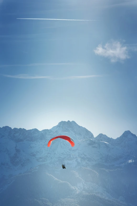 a man para - sailing over the mountains on a bright day