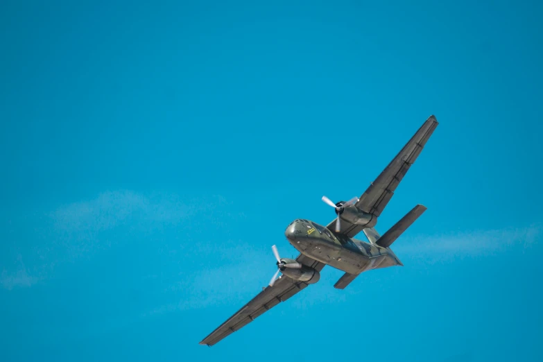 a military airplane flying with two propellors