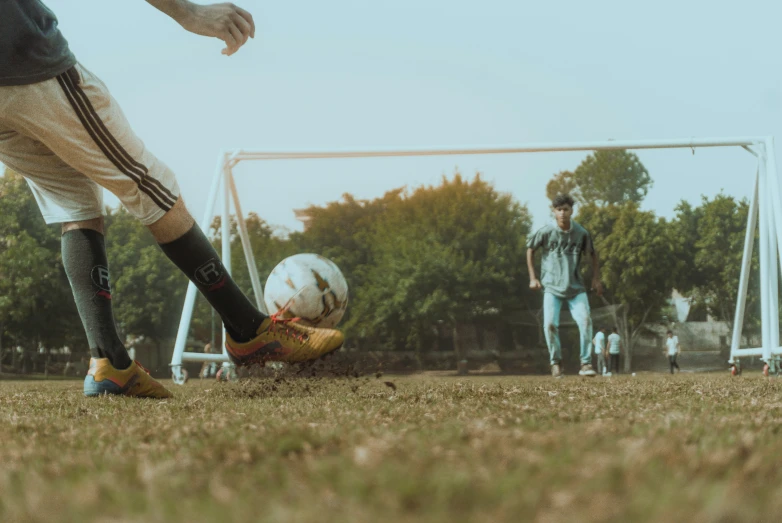 a soccer ball being placed on the ground as two men are in the background playing soccer