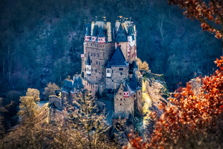 a castle is sitting next to trees on the edge of the hill