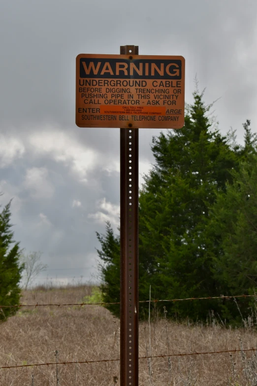 a warning sign next to the edge of a field