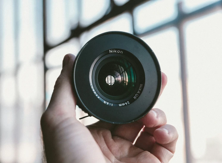 a person holding a camera lens in their left hand