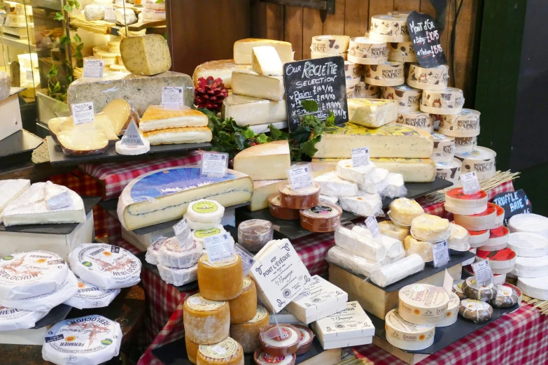 various cheeses, jams, and other food items on tables at an outside market