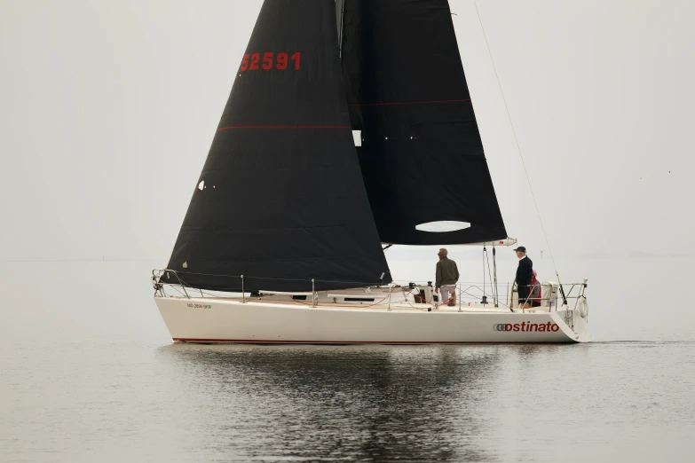 a person on a small sailboat with another on the water