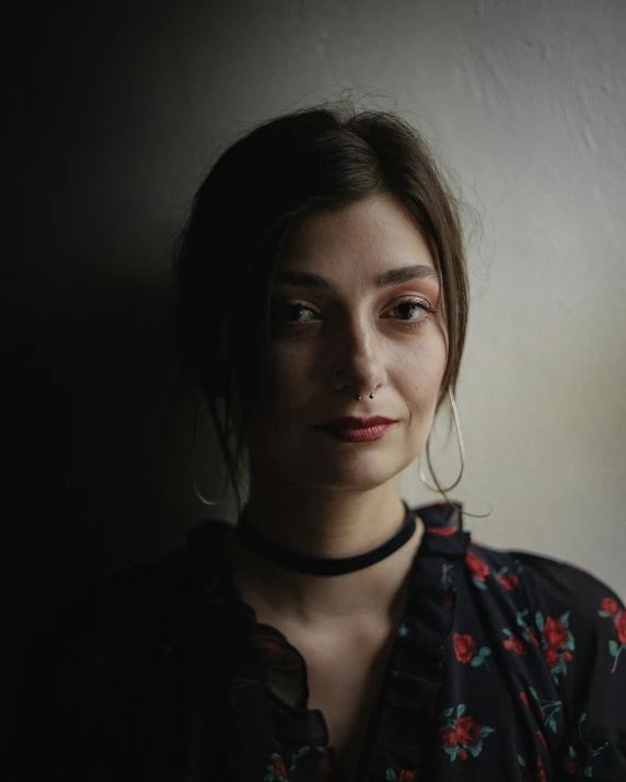 a woman with ear hoop wearing black and floral blouse