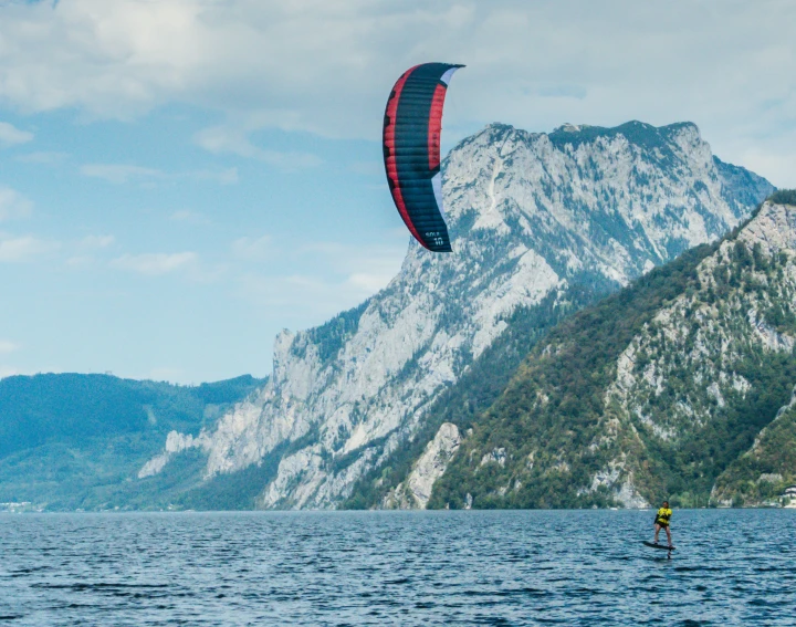 a kite boarder sailing on the water in front of a mountain range