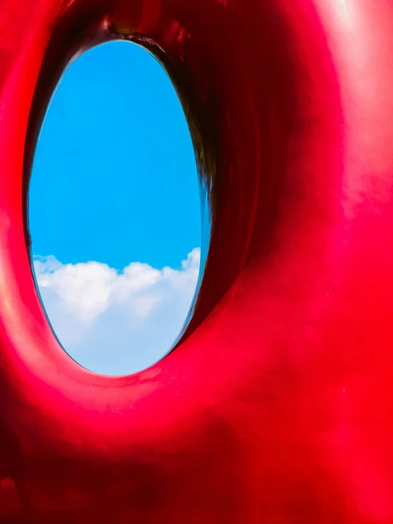 the reflection of the sky in a big red sculpture