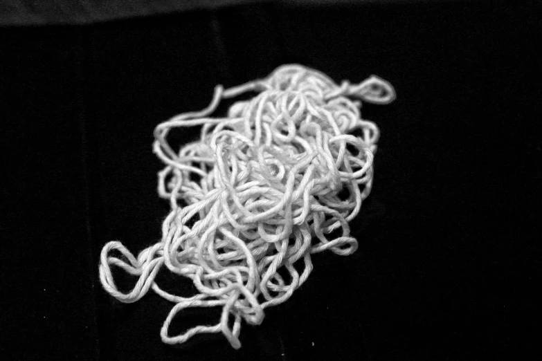 closeup of white yarn in small pile on black velvet surface