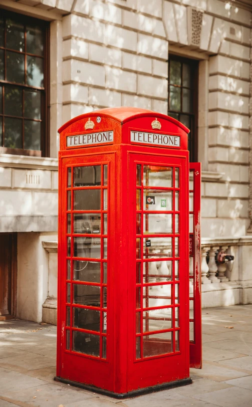 a red telephone booth in front of a stone building