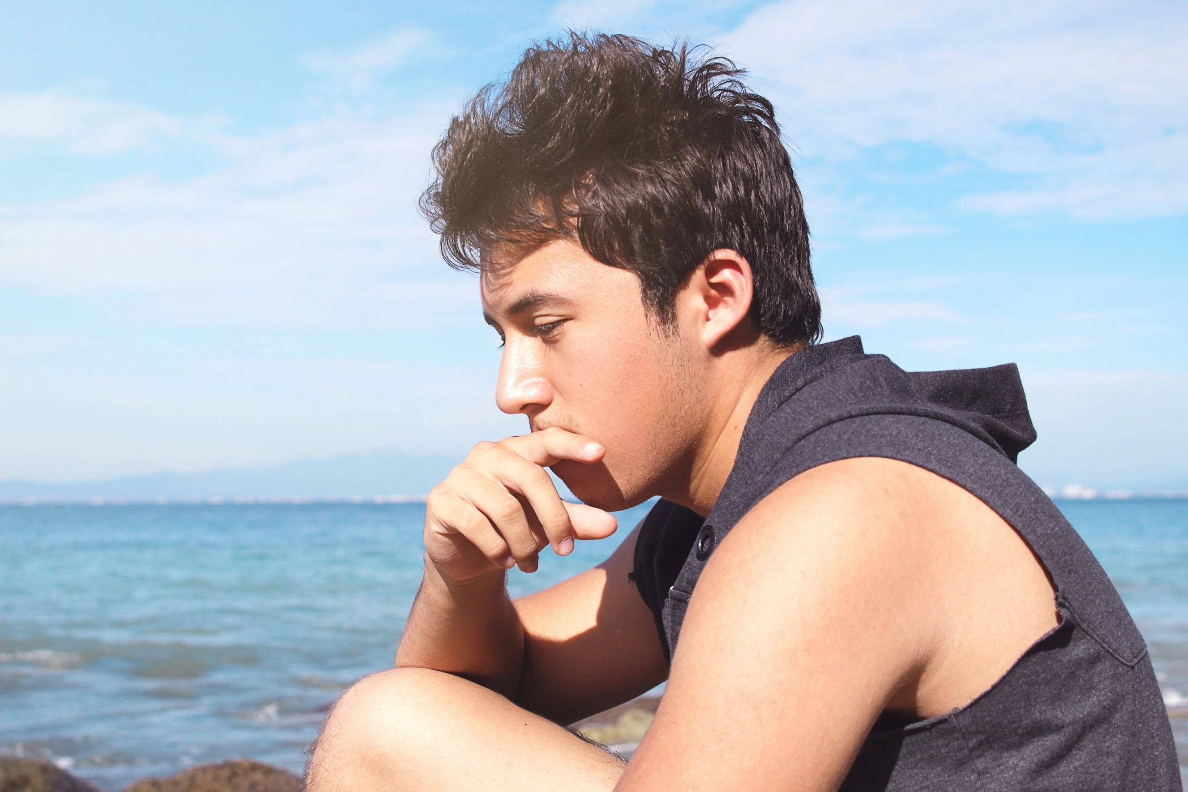 a man sits on a rock overlooking the water