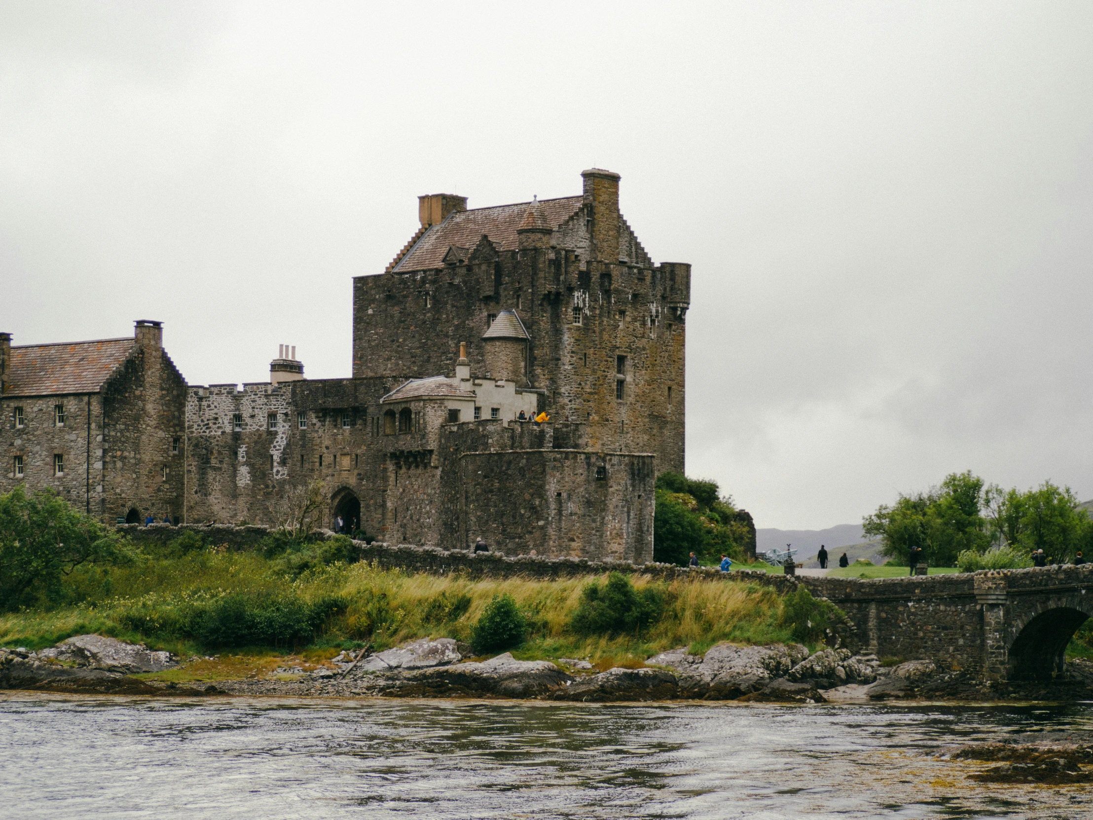 castle next to an old stone bridge, surrounded by green grass