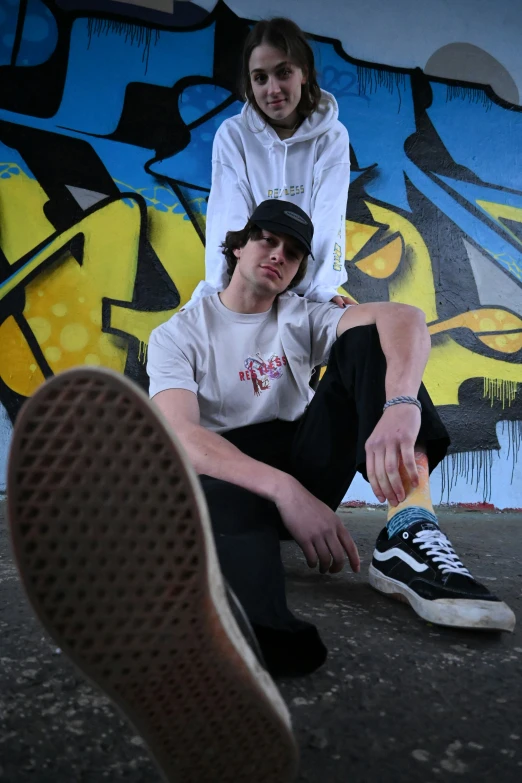 a man kneeling next to a girl in a white shirt