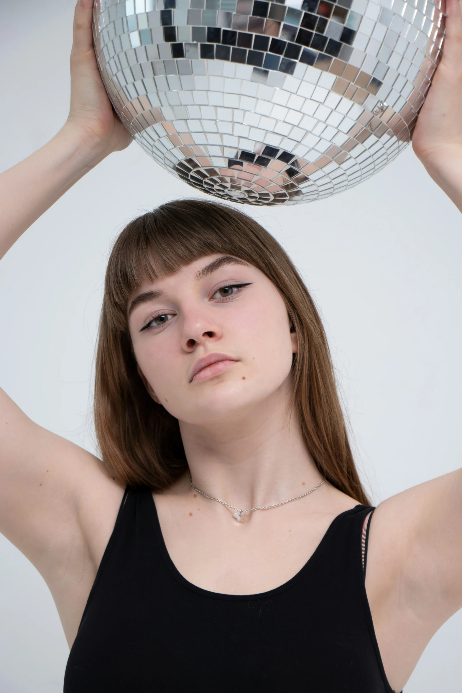 a woman holding up a disco ball to her face