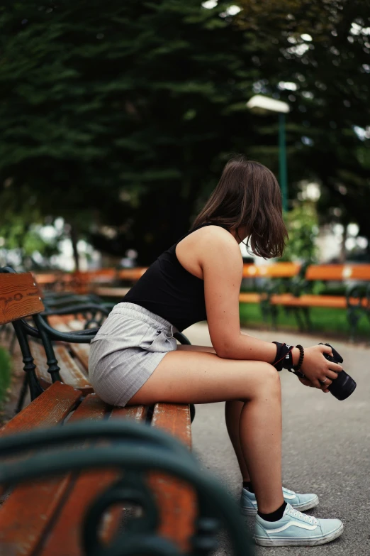 girl sitting on bench with cell phone in hand