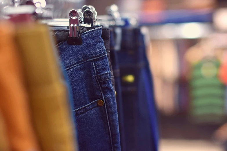 a close up of several different colored pants on hooks