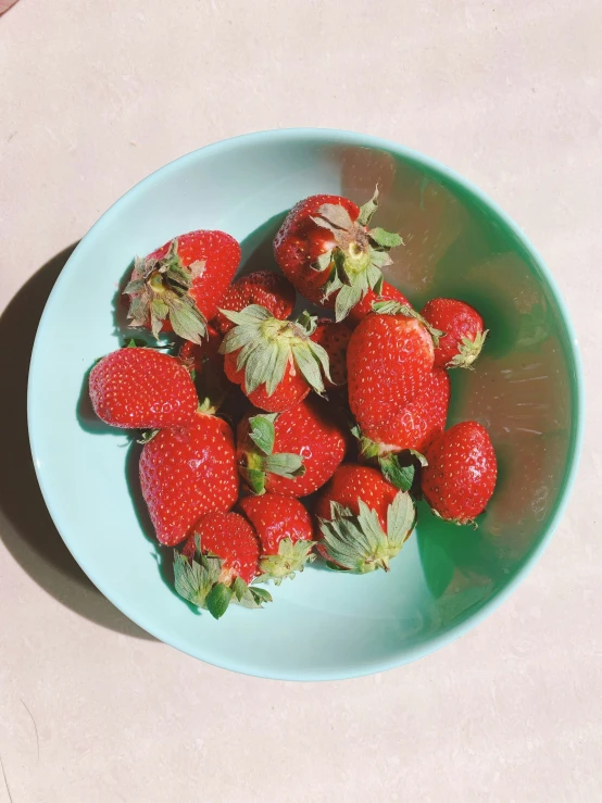 a plate of strawberries on top of a beige table