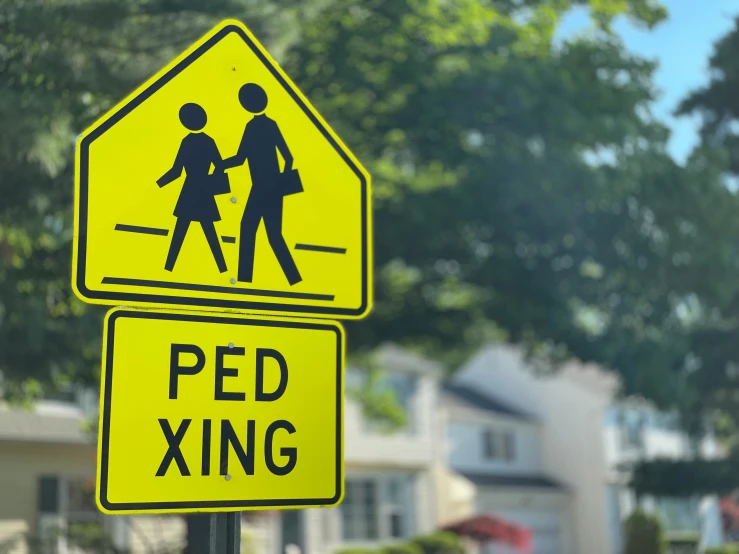 a yellow pedestrian crossing sign is in front of a couple