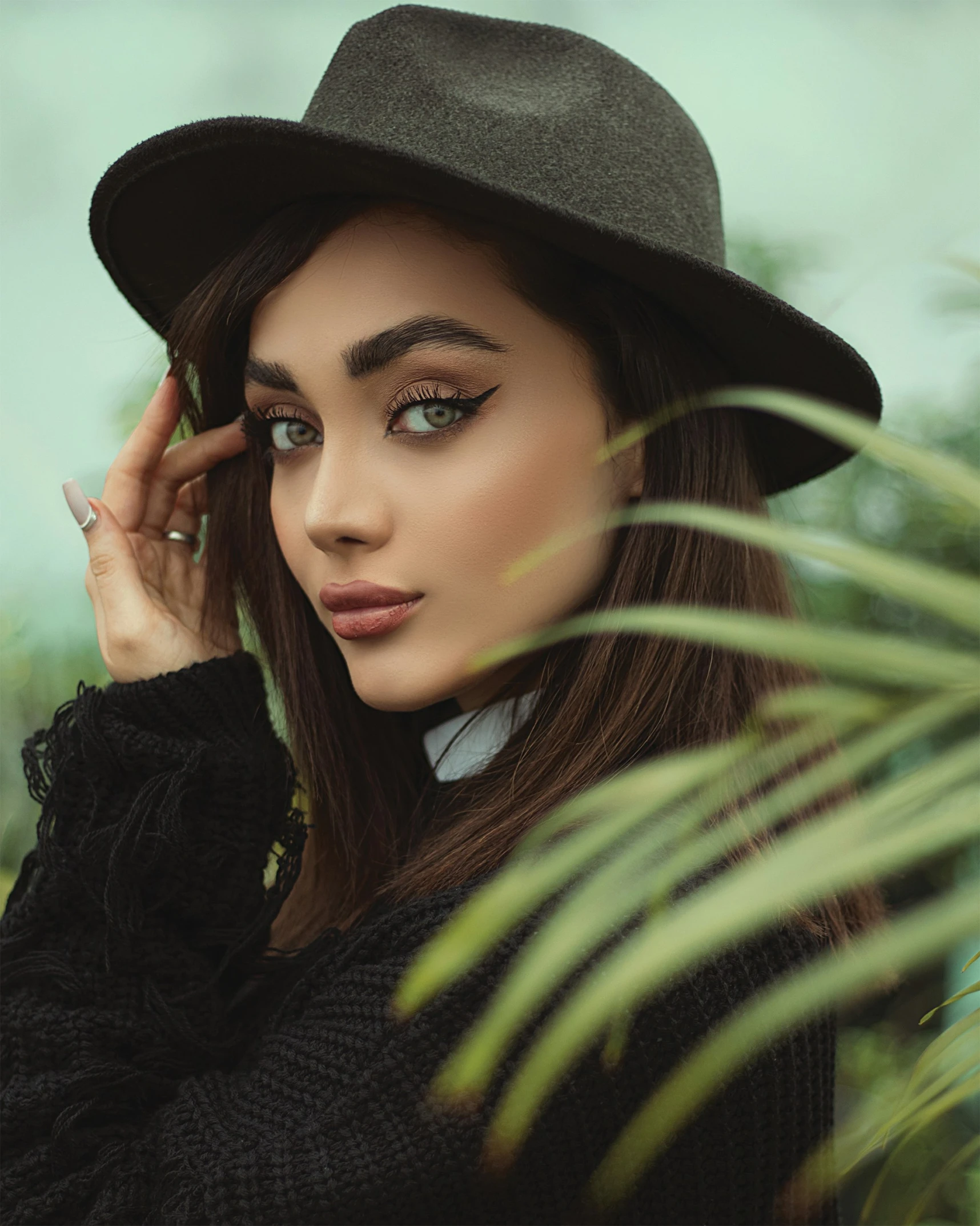 woman in hat standing among palm trees and foliage