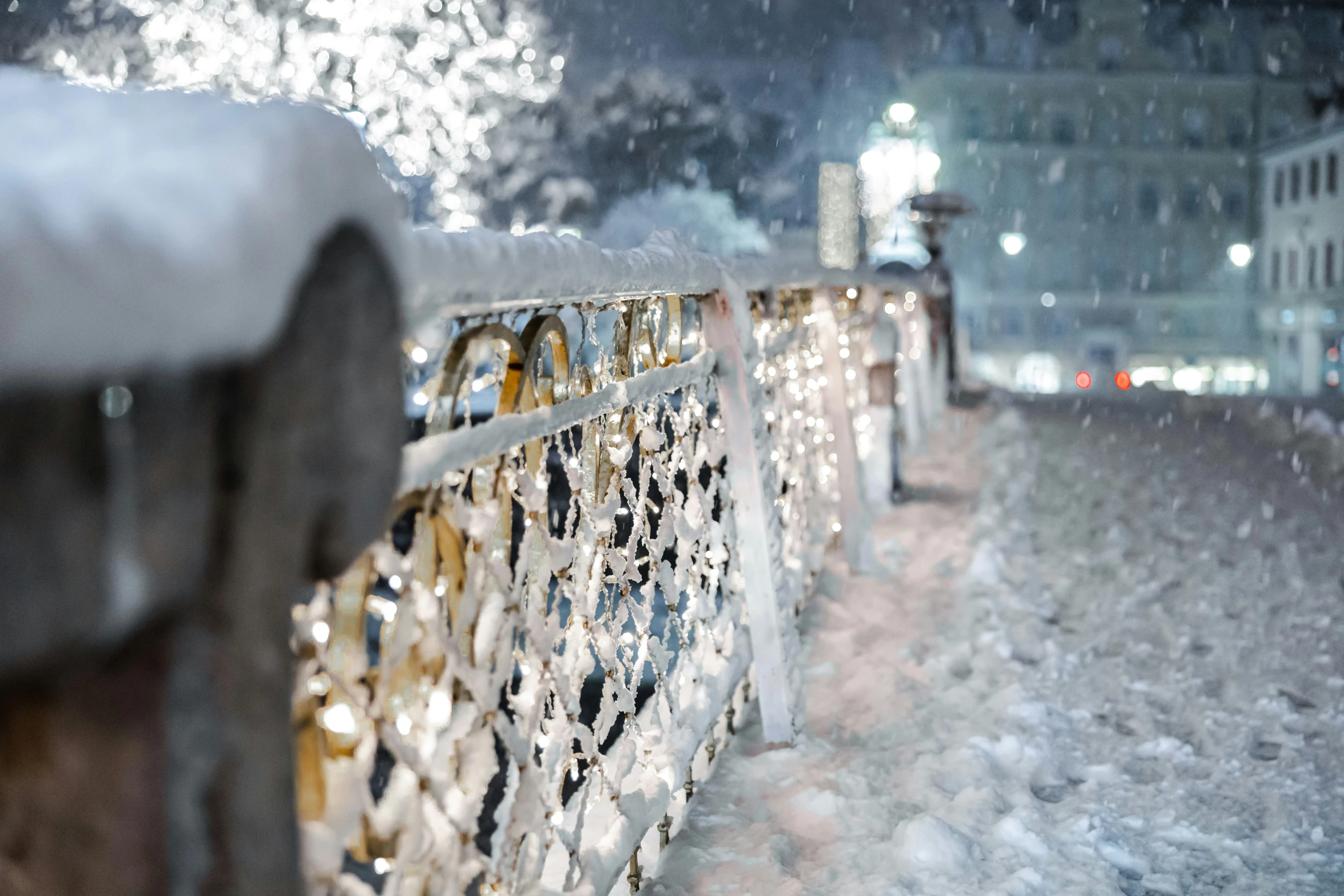 a metal railing in the snow by a building