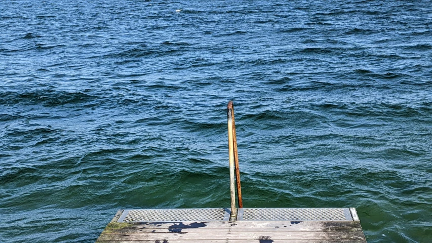 an old pier with a sail in the middle of a body of water