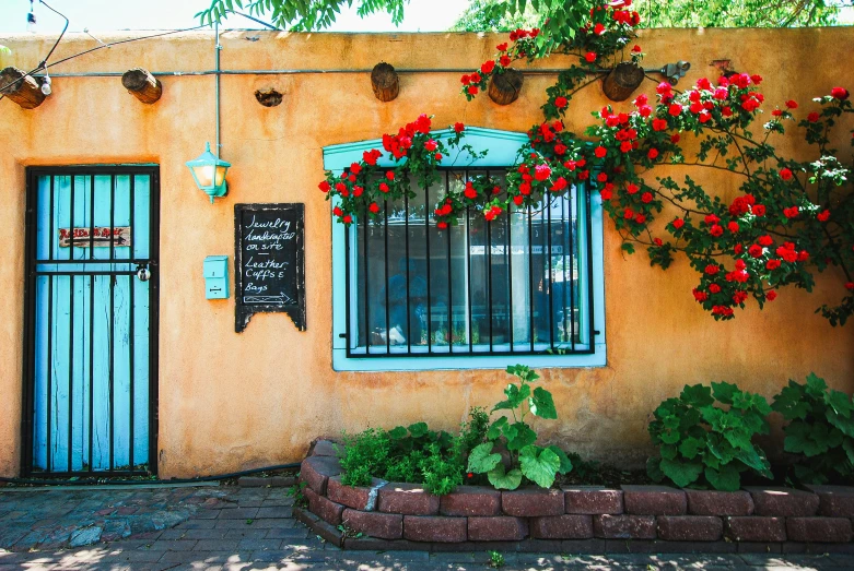 an orange building with some red flowers on the outside