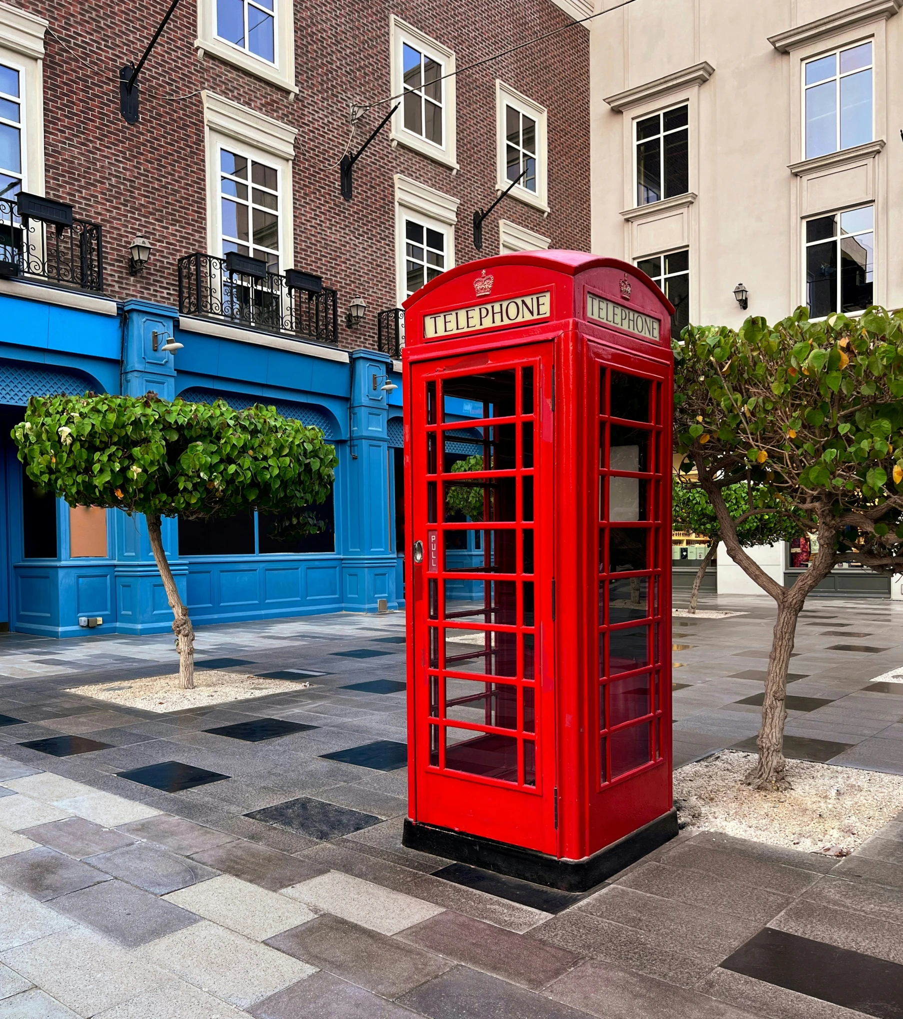 a red phone booth sits in the middle of the courtyard