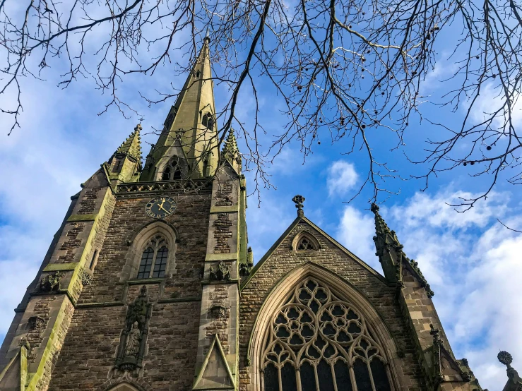 a large cathedral with trees and clouds in the background