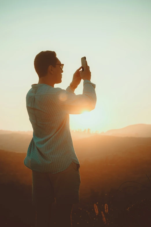 a man looking at his cell phone as the sun rises